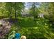 Grassy backyard area with mature trees, wooden fence and seating area at 1052 Barley Cir, Carmel, IN 46032