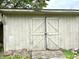 Exterior view of shed, showcasing double doors, aging white paint and surrounding yard growth at 106 S Hancock St, Waynetown, IN 47990