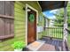 Inviting front porch featuring a wooden door with wreath and a welcome mat, set against green siding at 10854 E 700 N, Wilkinson, IN 46186