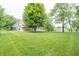 Spacious green backyard with mature trees, patio, and home featuring a deck and walkout basement at 11020 Florida Rd, Fortville, IN 46040