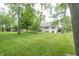 Lush green backyard with mature trees, stone patio, and home featuring a deck and walkout basement at 11020 Florida Rd, Fortville, IN 46040
