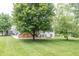 Spacious backyard with lush green grass, mature trees, a wooden deck, and a home with stone accents at 11020 Florida Rd, Fortville, IN 46040