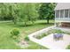 Outdoor stone patio with a table and chairs, surrounded by a lush garden and mature trees at 11020 Florida Rd, Fortville, IN 46040