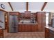 Spacious kitchen with stainless steel refrigerator, a wine rack, granite countertops, and wood beam accents at 11020 Florida Rd, Fortville, IN 46040