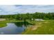 Overhead view showcasing the home surrounded by a large pond, lush greenery, and a spacious field at 12383 S 25 W, Columbus, IN 47201