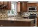 Kitchen with granite countertops, wood cabinets, stainless steel appliances, bright window, and mosaic backsplash at 12383 S 25 W, Columbus, IN 47201