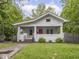 Charming bungalow with a red front door, white brick facade, and landscaped front yard, surrounded by mature trees at 1617 E 52Nd St, Indianapolis, IN 46205
