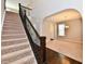 Elegant staircase with dark wood railings and neutral carpeting, leading to a naturally lit living space at 18726 Tillamook E Run, Noblesville, IN 46062