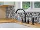 Close up of the kitchen sink, featuring butcher block countertops, a black faucet, and black and white tile backsplash at 2645 Washington St, Columbus, IN 47201