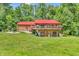 Beautiful log home with a red metal roof and a wraparound porch, surrounded by lush greenery at 2780 W Grizzly Trl, Martinsville, IN 46151