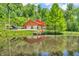 Scenic view of a log home with a red metal roof, complemented by a serene pond and dock at 2780 W Grizzly Trl, Martinsville, IN 46151