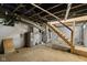 Unfinished basement with painted walls, exposed beams, duct work, and wooden stairs at 3227 Guilford Ave, Indianapolis, IN 46205