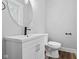 Modern bathroom with a stylish vanity, sink, toilet, and a large round mirror at 3227 Guilford Ave, Indianapolis, IN 46205
