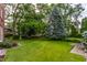 Lush green backyard with mature trees, landscaping, and a patio area for outdoor relaxation at 5165 E Pleasant Run Pkwy S Dr, Indianapolis, IN 46219