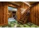 View of a wood-paneled basement with a staircase and an open doorway to a living room with a fireplace at 5165 E Pleasant Run Pkwy S Dr, Indianapolis, IN 46219