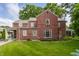 Rear view of a charming two-story brick home with a lush green lawn and mature trees, offering a serene outdoor space at 5165 E Pleasant Run Pkwy S Dr, Indianapolis, IN 46219