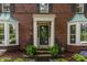 The front entrance with a black door is flanked by bay windows and ferns at 5165 E Pleasant Run Pkwy S Dr, Indianapolis, IN 46219