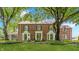 Charming brick two-story home with a manicured lawn, mature trees, and beautiful copper bay windows at 5165 E Pleasant Run Pkwy S Dr, Indianapolis, IN 46219