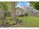 This backyard features a wooden patio with dining set and manicured landscaping around a mature tree at 5259 Broadway St, Indianapolis, IN 46220