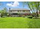 Large, verdant backyard featuring a well-manicured lawn, mature trees, and a patio with colorful chairs at 5419 Cayman Dr, Carmel, IN 46033