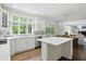 View of the kitchen island, white cabinetry, stainless appliances, and dining area with wood table at 5419 Cayman Dr, Carmel, IN 46033