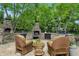 Outdoor stone kitchen with bar seating features a grill and is shaded by mature trees at 5419 Cayman Dr, Carmel, IN 46033