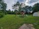 Large backyard featuring a wooden playset, green lawn, and storage shed at 5515 Lunsford Dr, Indianapolis, IN 46237