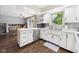 Bright kitchen boasts white cabinets, appliances, and wood flooring with view to dining area at 5542 N Olivia Dr, Alexandria, IN 46001