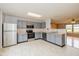 Well-lit kitchen boasts stainless steel appliances, gray cabinets, and an efficient layout, seamlessly connected to the living area at 560 Tracy Ln, Brownsburg, IN 46112