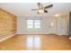 Bright living room with wood-look floors, a modern ceiling fan, and a view of the front yard through large windows at 560 Tracy Ln, Brownsburg, IN 46112