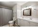 Bright bathroom with double sinks, white cabinetry, modern fixtures, and a shower with tiled wall at 5873 N Victoria Dr, Indianapolis, IN 46228