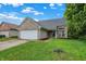Traditional brick home featuring a manicured lawn, two car garage, and a welcoming entryway with blue skies at 6010 Lakeside Manor Ave, Indianapolis, IN 46254