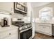 White kitchen featuring a gas range stove, white cabinets, subway tile backsplash, and stone countertops at 6040 Crittenden Ave, Indianapolis, IN 46220