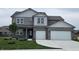 Charming two-story home featuring a two-car garage, gray brick, lush lawn and manicured landscaping at 6049 Madera Dr, Whitestown, IN 46075