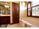 Bright bathroom featuring a jacuzzi tub, dark wood cabinets, and decorative windows with etched glass at 6412 Fall Creek Rd, Indianapolis, IN 46220