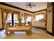 Cozy bedroom featuring an ornate gold bench, ceiling fan, and French doors at 6412 Fall Creek Rd, Indianapolis, IN 46220