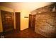 Hallway featuring hardwood floors and a brick accent wall, connecting various rooms within the house at 6412 Fall Creek Rd, Indianapolis, IN 46220
