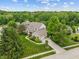 Aerial view of a stunning brick home with lush landscaping, a long driveway, and mature trees at 7141 Ember Ct, Indianapolis, IN 46236