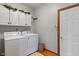 A well-organized laundry room featuring a washer, dryer, storage cabinets, and a door to the outside at 7141 Ember Ct, Indianapolis, IN 46236