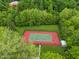 Aerial view of a tennis court surrounded by mature trees and green space. with lighting for night games at 7141 Ember Ct, Indianapolis, IN 46236