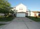 Two-story home with light yellow siding, a brick foundation, and an extended driveway featuring a basketball hoop at 8609 Wheatfield Dr, Camby, IN 46113