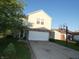 Two-story home with light yellow siding, a brick foundation, and an extended driveway featuring a basketball hoop at 8609 Wheatfield Dr, Camby, IN 46113