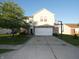 Two-story home with light yellow siding, a brick foundation, and an extended driveway featuring a basketball hoop at 8609 Wheatfield Dr, Camby, IN 46113