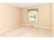 A simple bedroom with a beige carpet, neutral walls, and a window overlooking the outdoor landscape at 8713 Champions Dr, Indianapolis, IN 46256