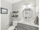 Stylish half bath with modern vanity, marble countertop, and decorative shelving at 10697 Woodmont Ln, Fishers, IN 46037