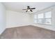 A carpeted room with a ceiling fan and large windows at 107 Elliott Ave, Trafalgar, IN 46181