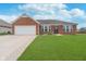 Charming brick home featuring an attached two car garage, well-maintained lawn and partial landscaping at 107 Elliott Ave, Trafalgar, IN 46181