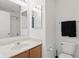 Bright bathroom features a wood vanity, large mirror and toilet with dark towels hanging above at 10722 Landsbrook N Run, Noblesville, IN 46060