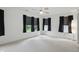 Spacious bedroom with neutral carpet offers three windows with dark curtains and a ceiling fan at 10722 Landsbrook N Run, Noblesville, IN 46060