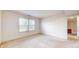 Sunlit bedroom with neutral walls and carpet, showcasing a large window and a hallway entrance at 1129 Central Park S Blvd, Greenwood, IN 46143